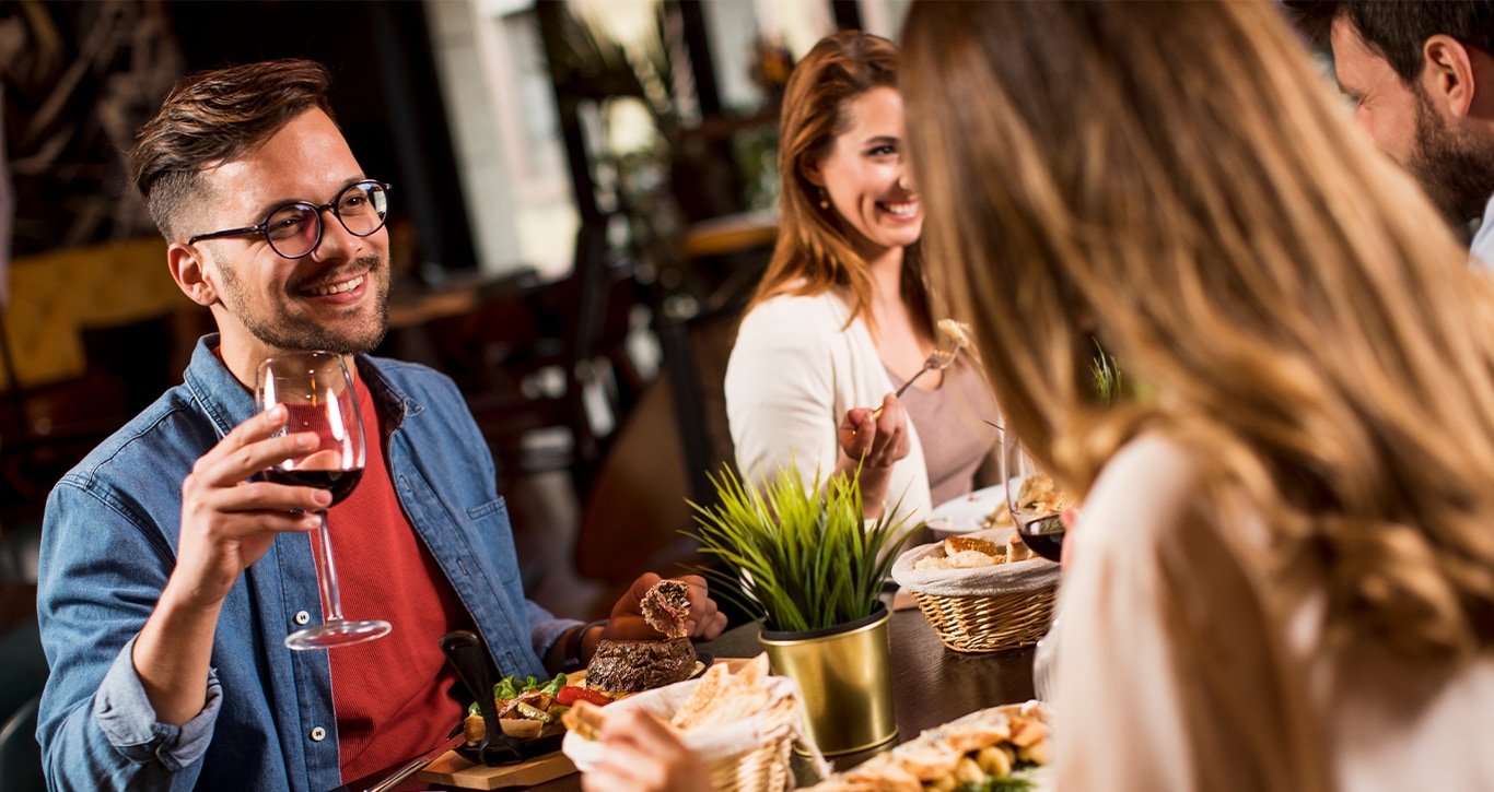 Volvo Dealer in Greensburg | Friends smiling and eating dinner together at a restaurant 