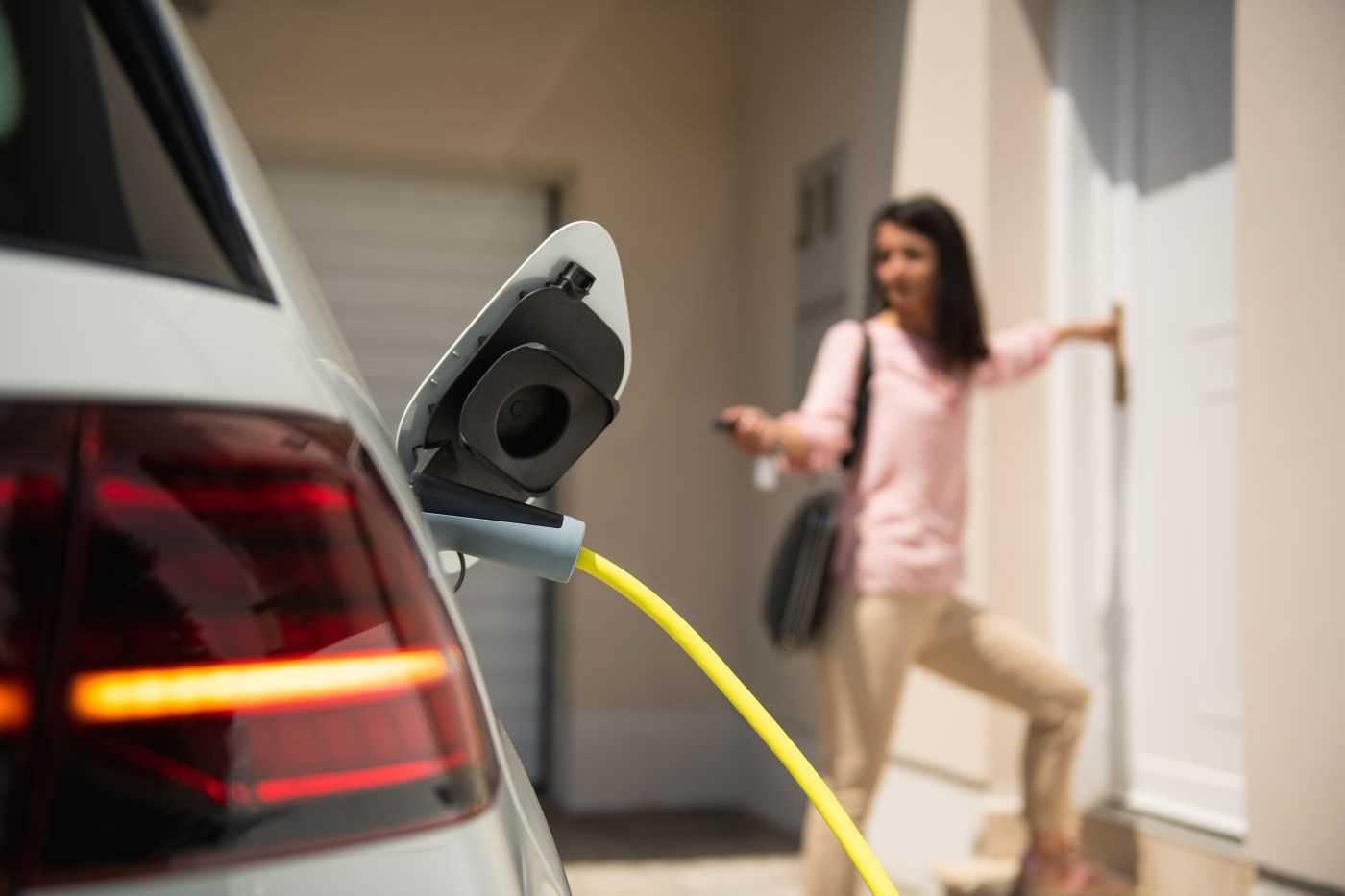 owner walking into home while electric car charges