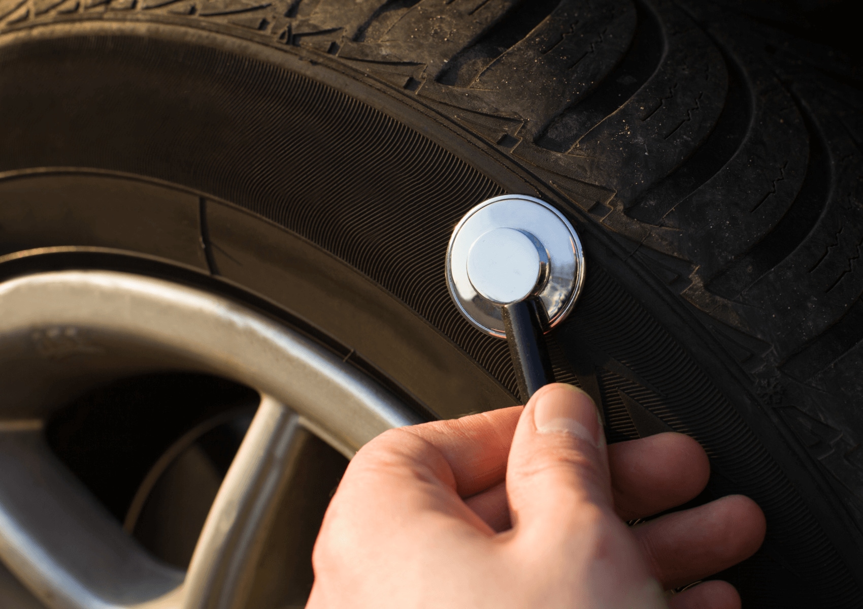 Mechanic looking for objects in tire with magnet