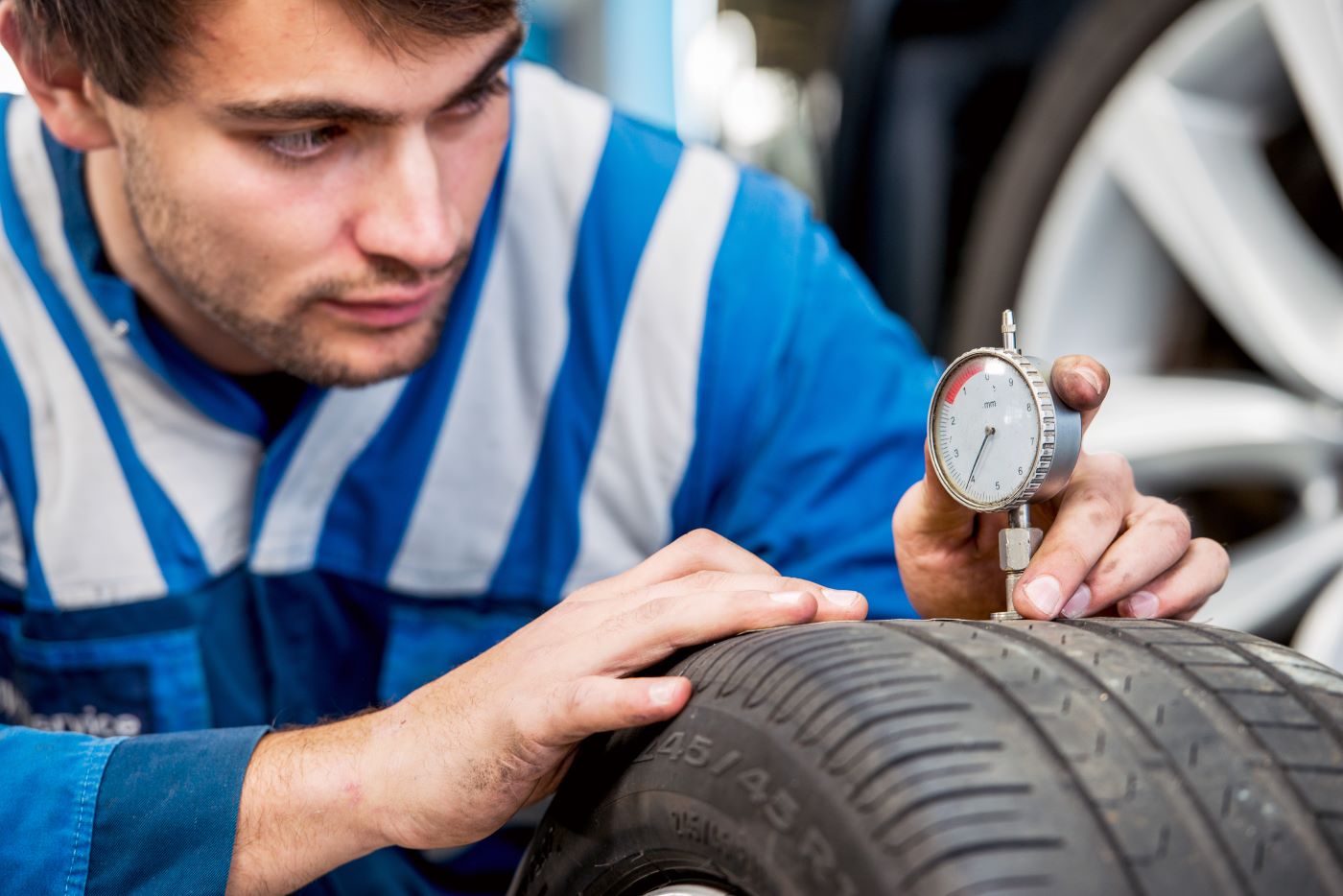 Mechanic checking tire pressure with gauge