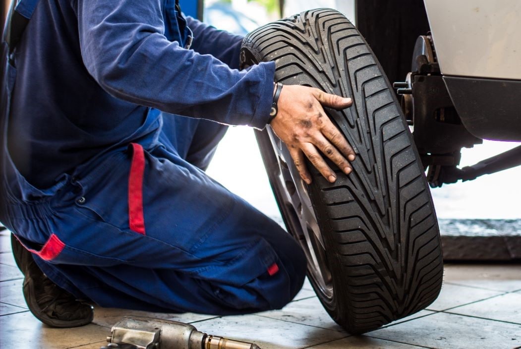 Mechanic completing tire repair and replacing new tire and wheel