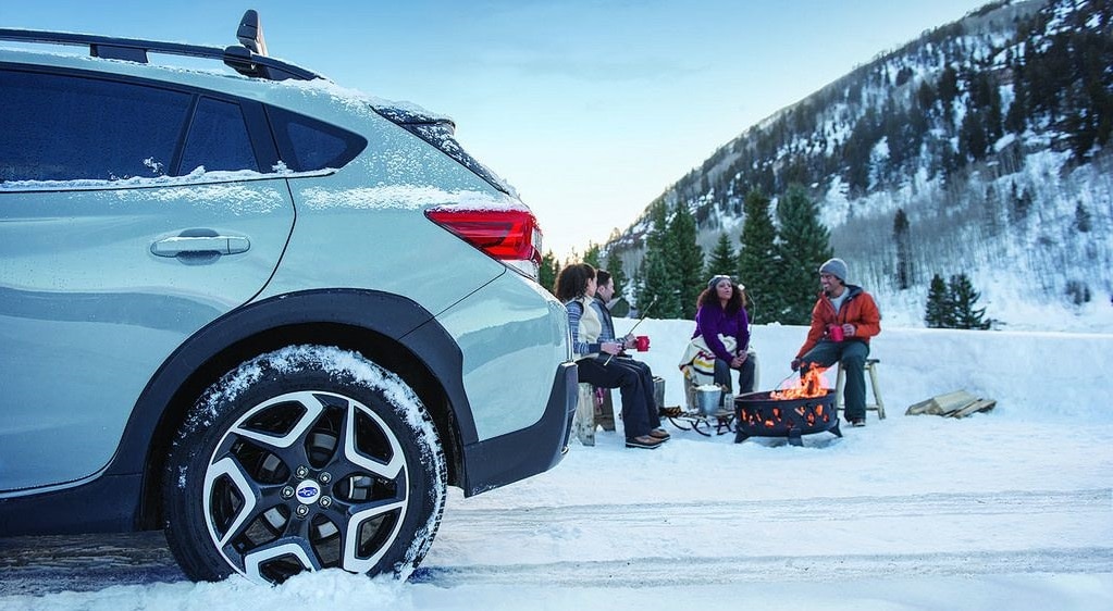 Friends Enjoying Winter Campfire Beside Parked Subaru