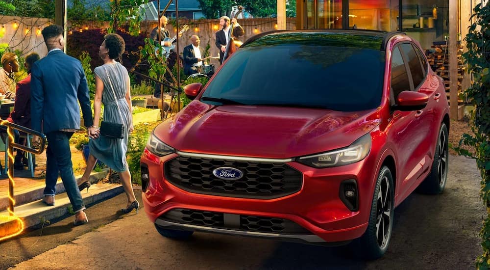 Left angled view of a red 2025 Ford Escape ST-Line parked outside a house.