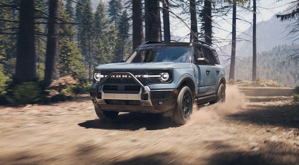 A blue 2025 Ford Bronco Sport Outer Banks is shown driving in a forest.