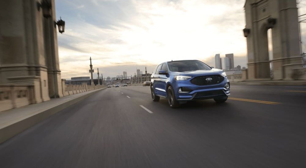 A blue 2021 Ford Edge is shown driving on a bridge.