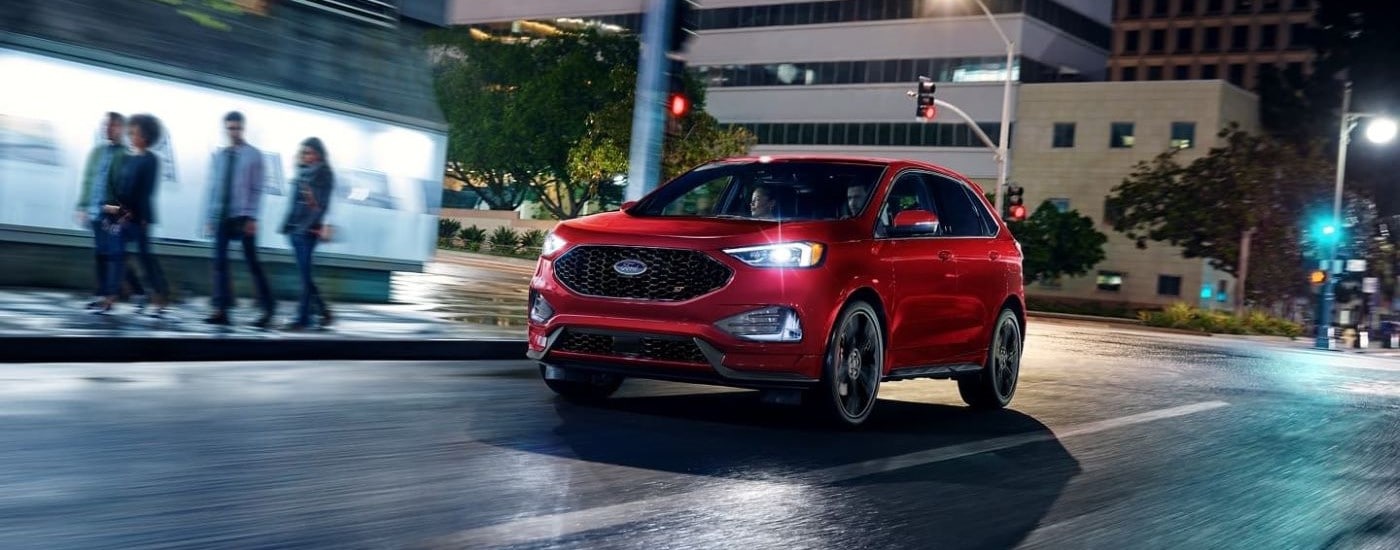 Red 2023 Ford Edge ST driving down a city street from a used Ford dealer near Medina.