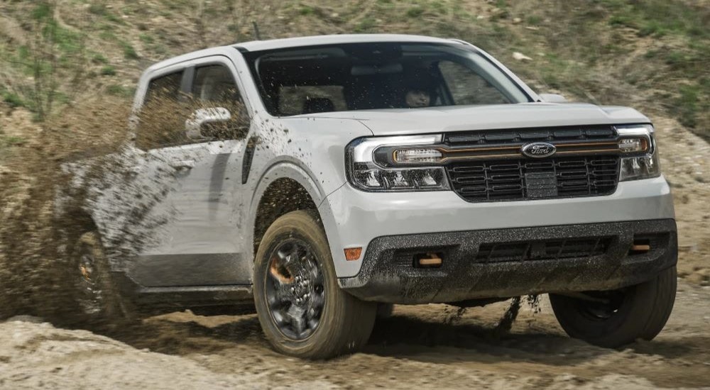 A white 2024 Ford Maverick Tremor kicking up dirt while driving off-road from a Ford dealer near Humboldt.