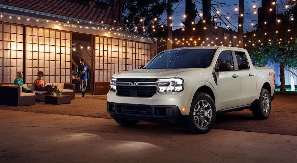 A grey 2024 Ford Maverick is parked on a patio below string lights.