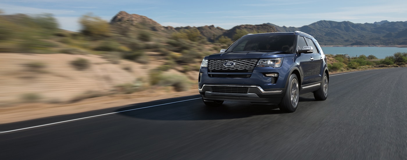 Blue 2018 Ford Explorer driving down a road from a used Ford dealer near Jackson.