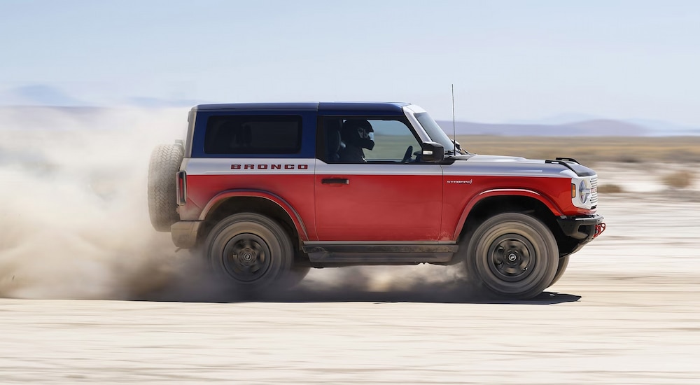 A red and white 2025 Ford Bronco Stroppe Edition racing across sand dunes.