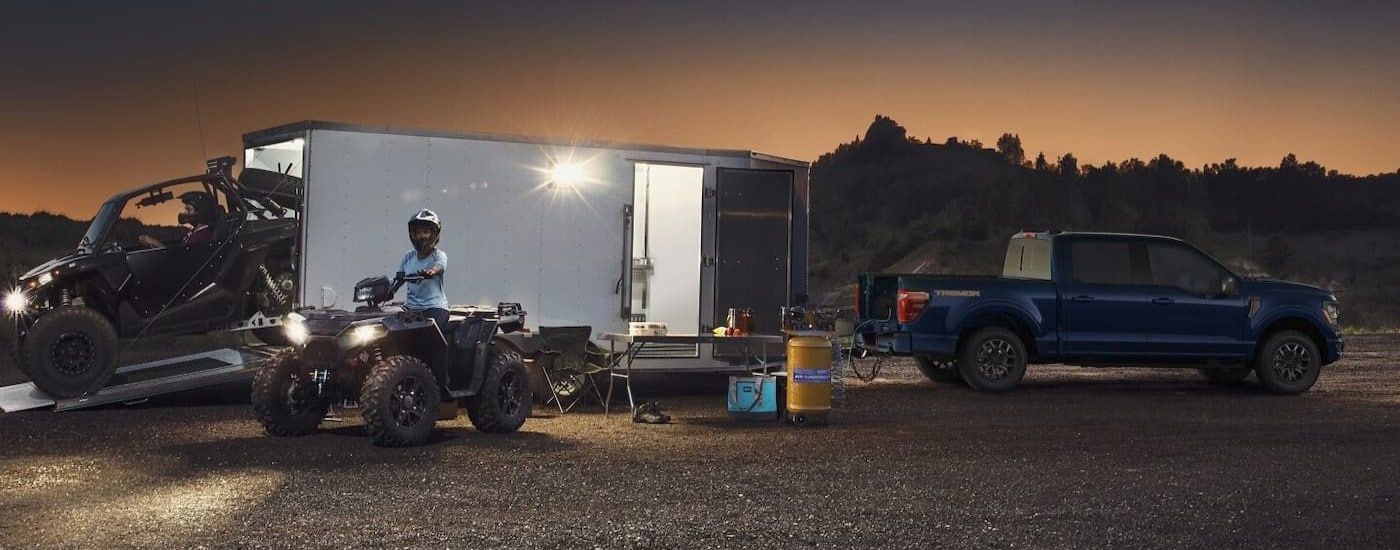 A blue 2025 Ford F-150 Tremor is shown parked while towing a trailer.