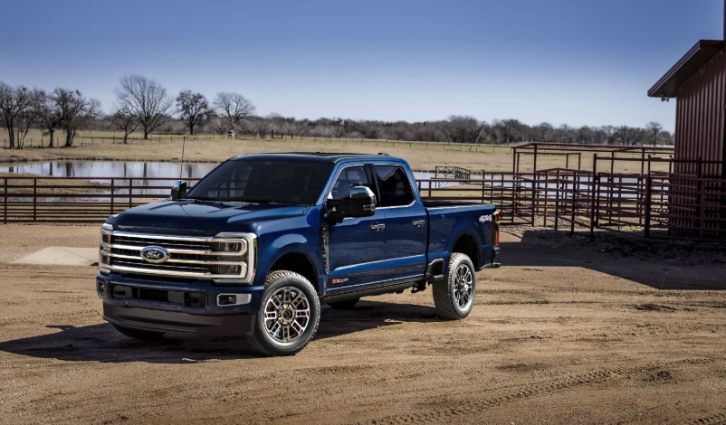 Two people exiting a 2025 Ford F-150® XLT pickup in Rapid Red hitched to a trailer of ATVs
