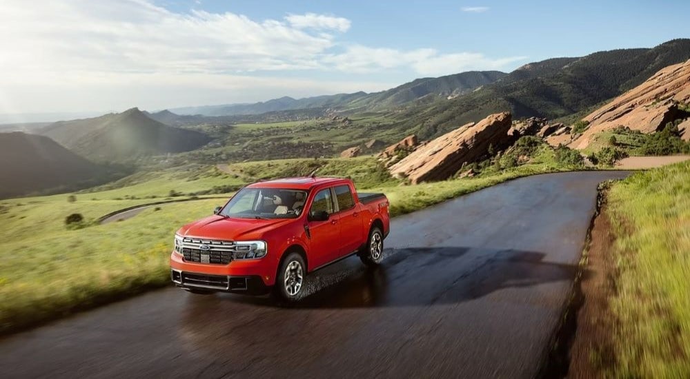 A red 2024 Ford Maverick driving through a mountain pass.