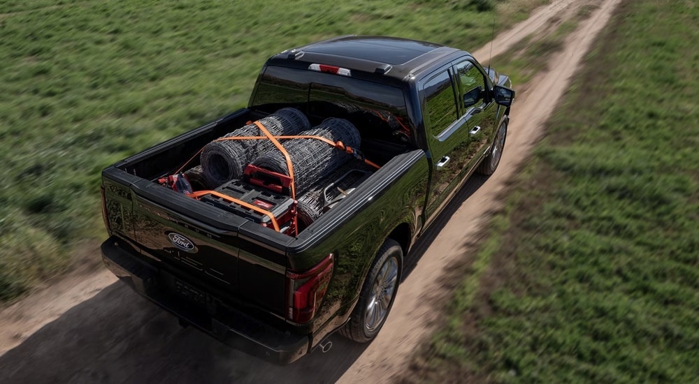 Overhead view of a black 2024 Ford F-150 Platinum driving with a load of farm materials in the bed of the truck