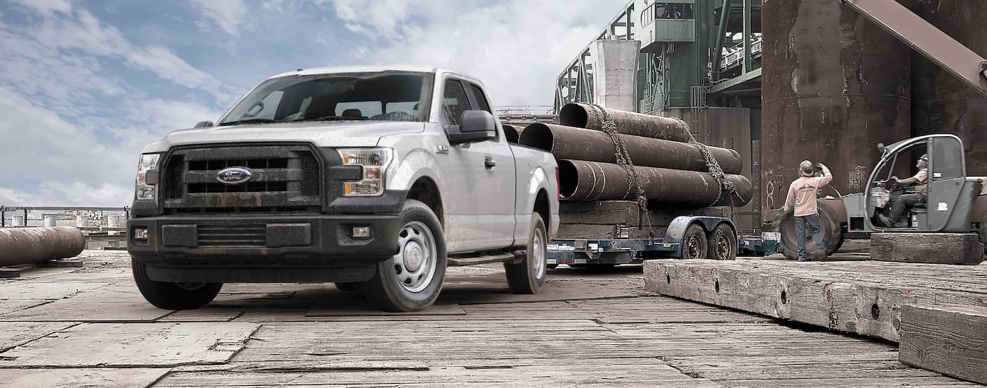 White 2015 Ford F-150 towing pipes near a construction site after visiting a used car dealer near Trenton.