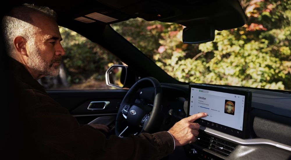A man using the infotainment screen in a 2025 Ford Explorer for sale in Milan.