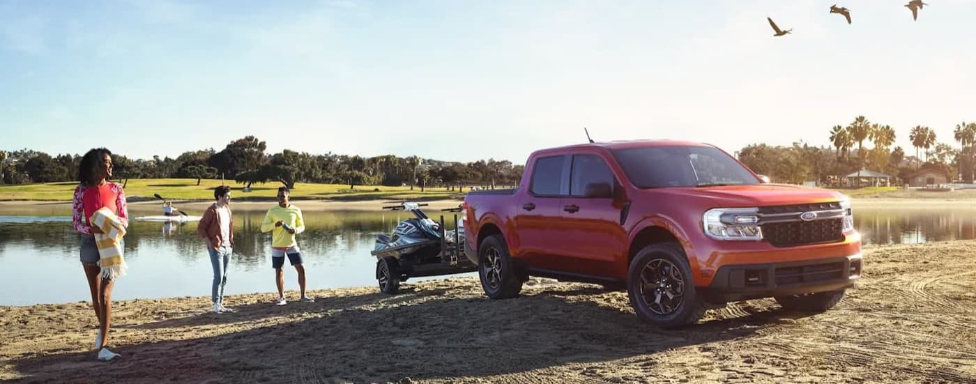 A red 2023 Ford Maverick parked near a lake.