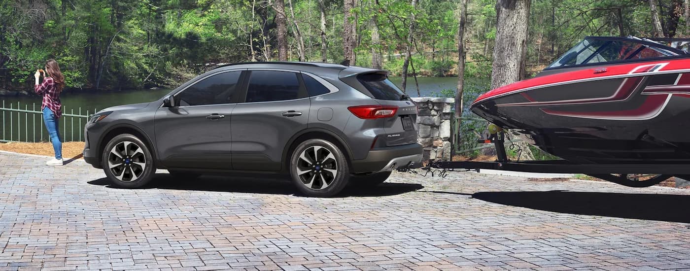 A grey 2025 Ford Escape for sale towing a boat.