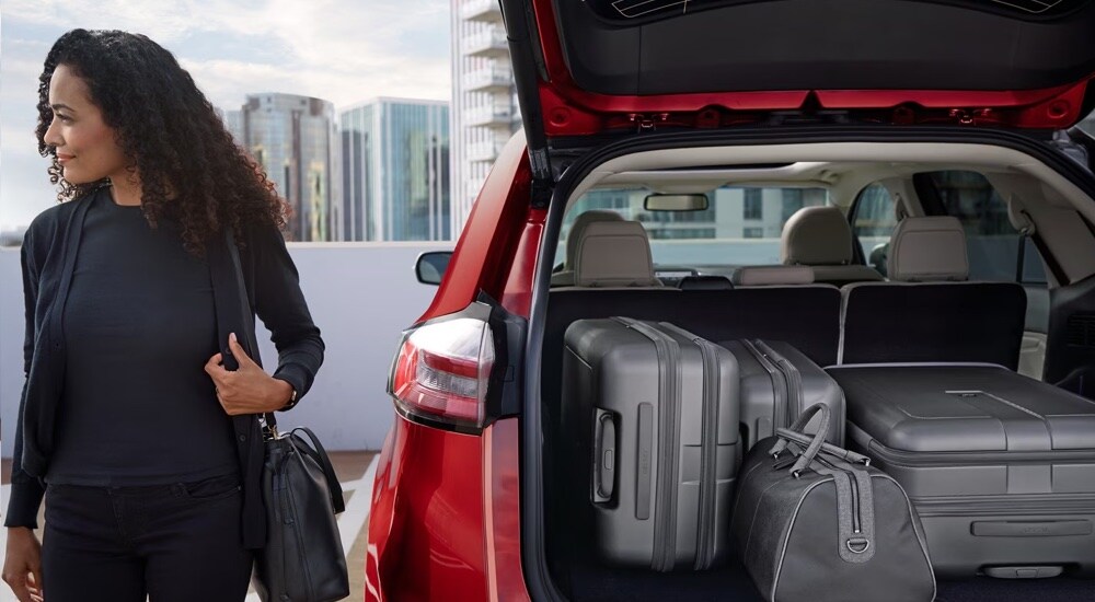 A woman standing near a set of luggage in the cargo area of a red 2024 Ford Edge.