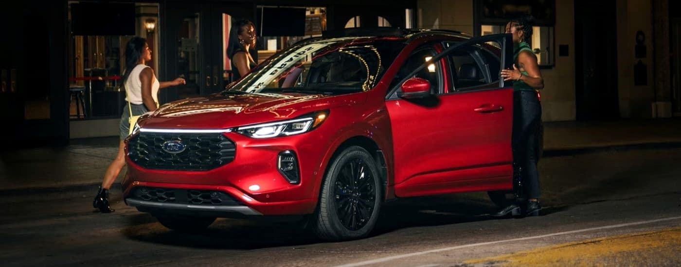 Two people entering a red 2023 Ford Escape ST-Line Elite angled left.