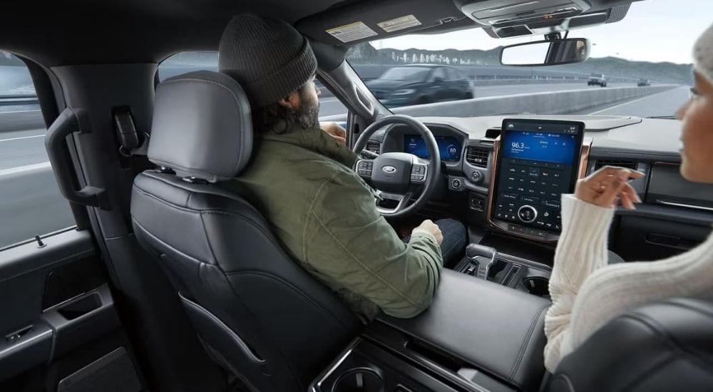 People are shown driving a 2022 Ford F-150 Lightning on a highway.