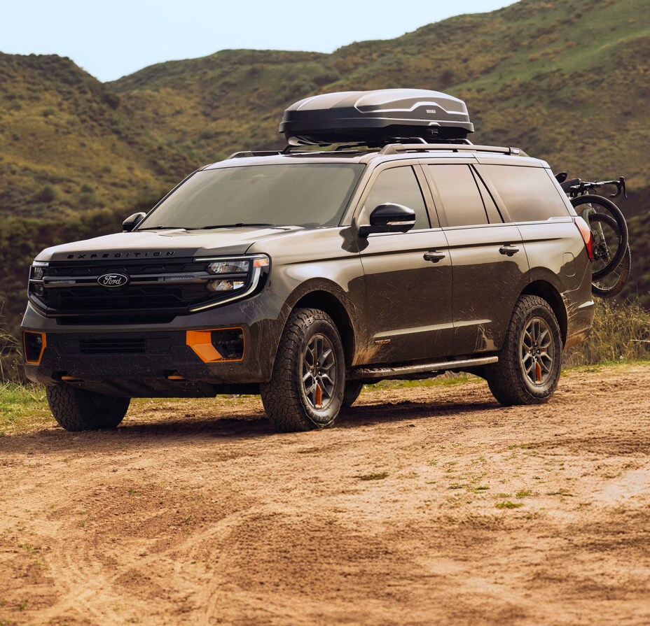 Two people exiting a 2025 Ford F-150® XLT pickup in Rapid Red hitched to a trailer of ATVs