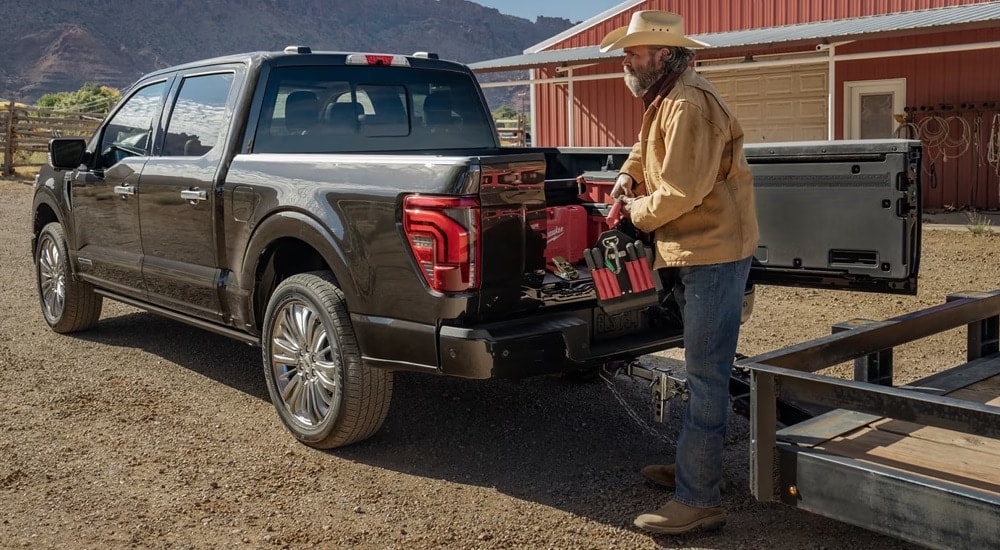 A farmer uses the Pro Access tailgate to access tools in the bed of his 2024 Ford F-150.