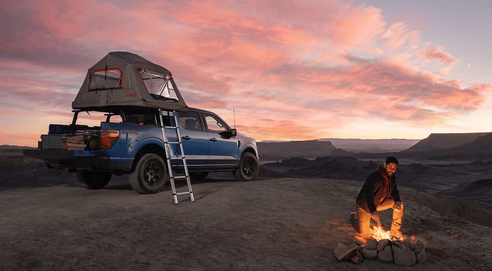 A blue 2025 F-150 STX is parked at a campsite in a remote area.