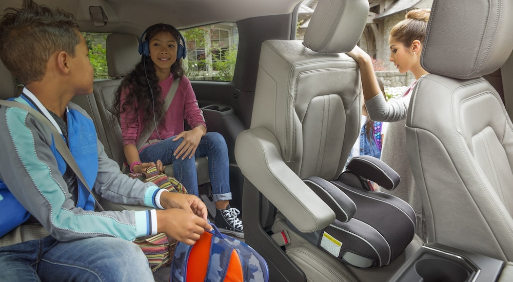 A woman using the Tip and Slide second-row seats to let kids out of a 2024 Ford Expedition.