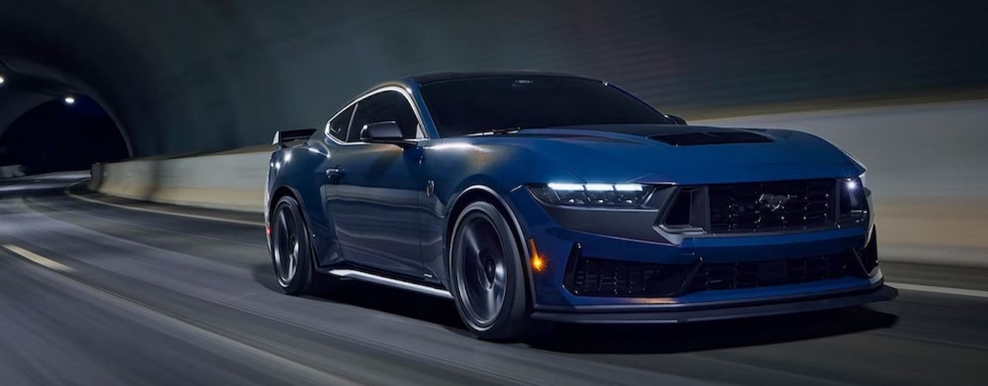 A blue 2024 Ford Mustang Dark Horse Premium is shown driving through a tunnel.