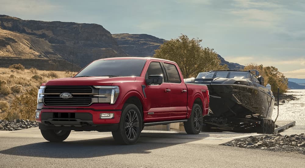 Red 2025 Ford F-150 Platinum towing a boat out of a lake.