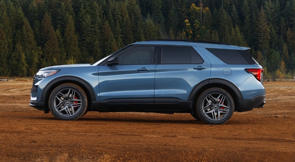 A blue 2025 Ford Explorer ST parked near a forest.