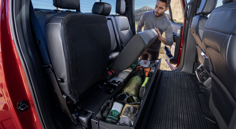 Person stowing gear in the back of a red 2025 Ford F-150.