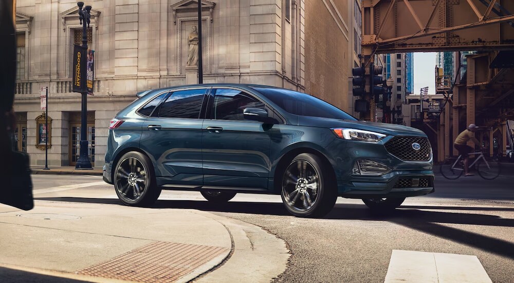 A blue 2024 Ford Edge driving around a city corner.