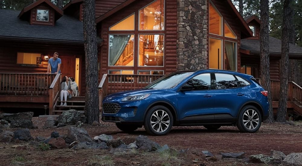 A blue 2022 Ford Escape is shown parked near a log cabin.