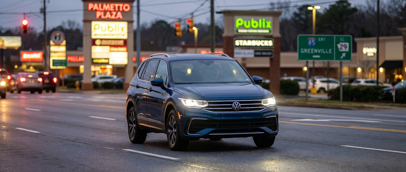 2026 Volkswagen Tiguan with LED headlights illuminated on a busy commercial road at night in Greenville, SC