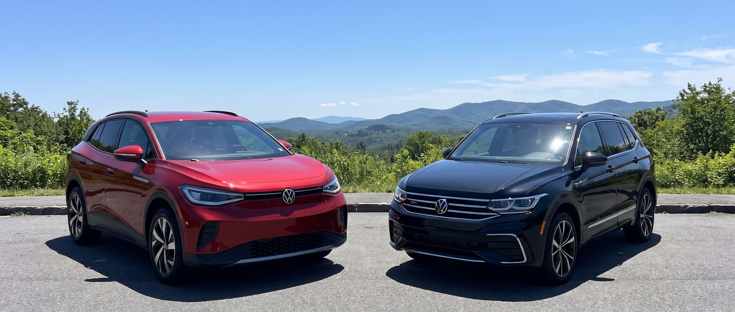 2026 Volkswagen ID.4 and 2026 Volkswagen Tiguan parked side by side near Greenville, SC with Blue Ridge foothills in the background