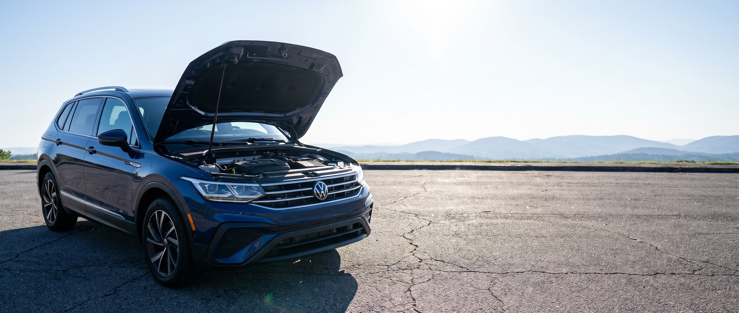 2026 Volkswagen Tiguan parked on hot Greenville SC asphalt with engine bay visible and summer heat shimmer rising from the pavement
