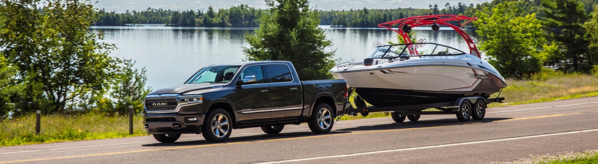 New Ram 1500 towing a boat by a lake