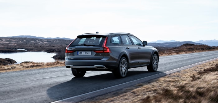New Volvo V90 Cross Country driving away down a road