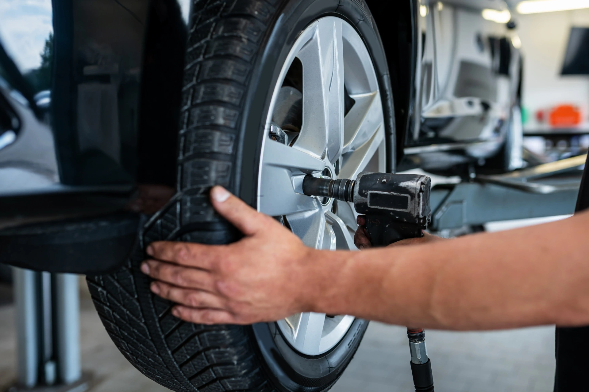 Technician using an impact wrench to rotate a tire in a service bay