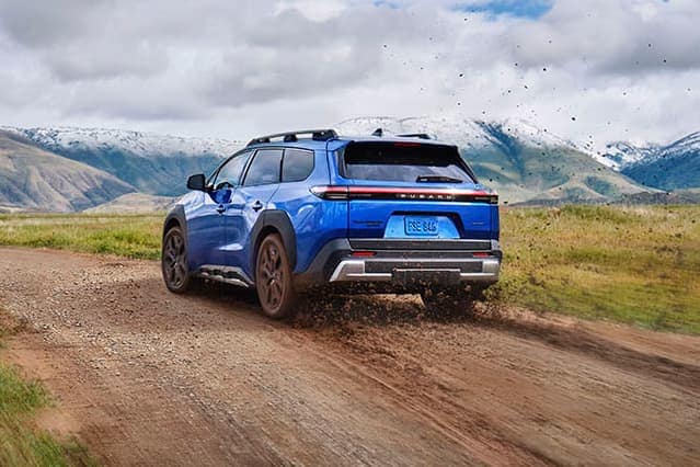 Subaru Trailseeker off-pavement electric SUV exterior rear angle view on muddy terrain.