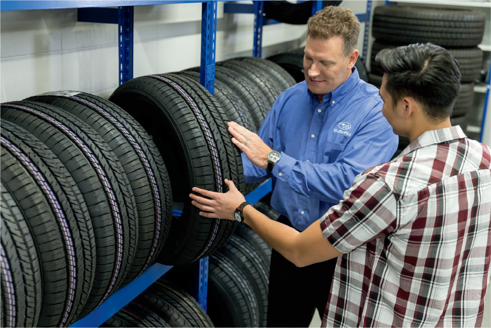 Customer looking at a tire with a Subaru certified technician