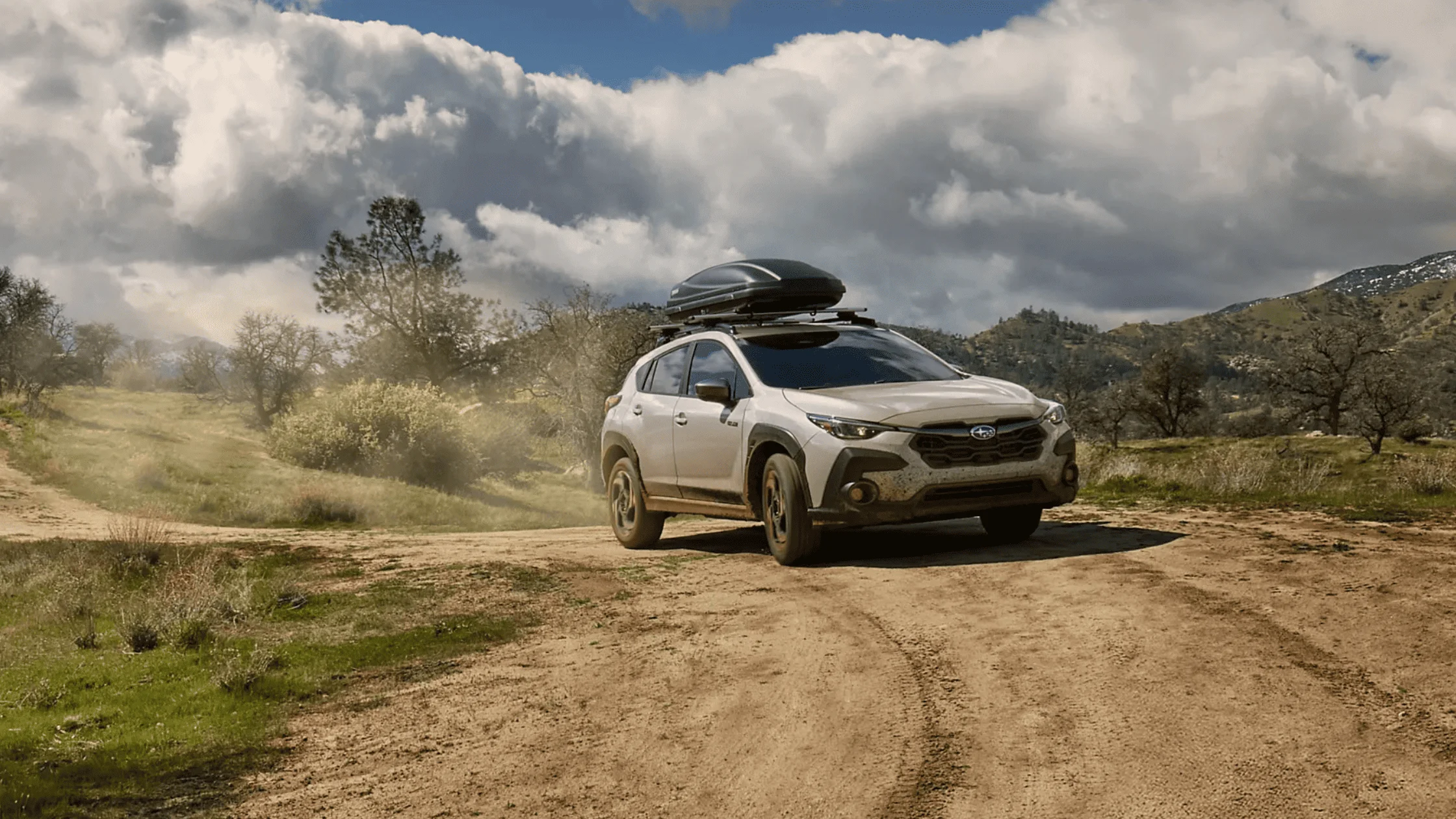 2026 Subaru Outback Wilderness in blue navigating a rocky off-road trail with roof rack in a desert canyon landscape, available in Pueblo CO