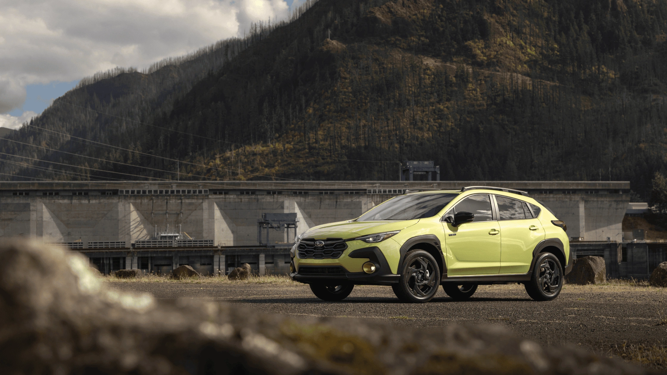 2026 Subaru Crosstrek Hybrid in lime green with black accents parked near mountain dam showcasing rugged off-road capability in Pueblo CO