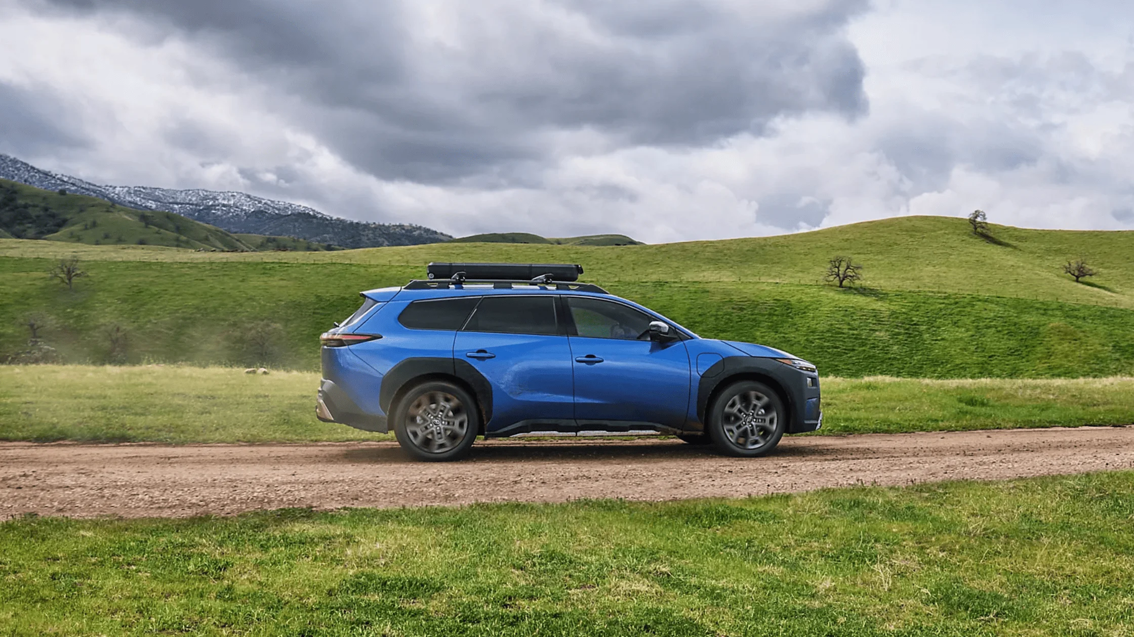 2026 Subaru Outback Wilderness in blue navigating a rocky off-road trail with roof rack in a desert canyon landscape, available in Pueblo CO
