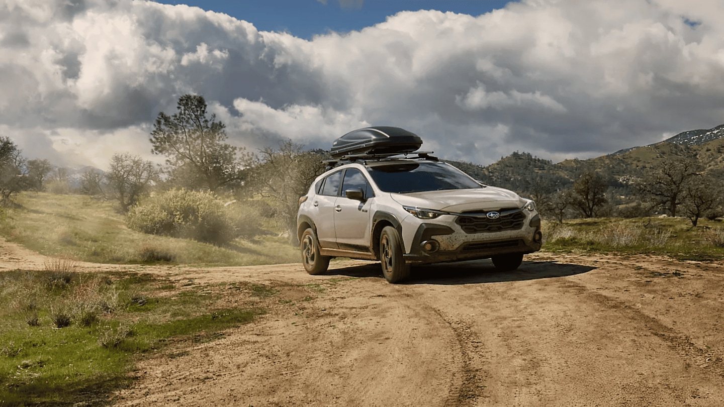 2026 Subaru Outback Wilderness in blue navigating a rocky off-road trail with roof rack in a desert canyon landscape, available in Pueblo CO