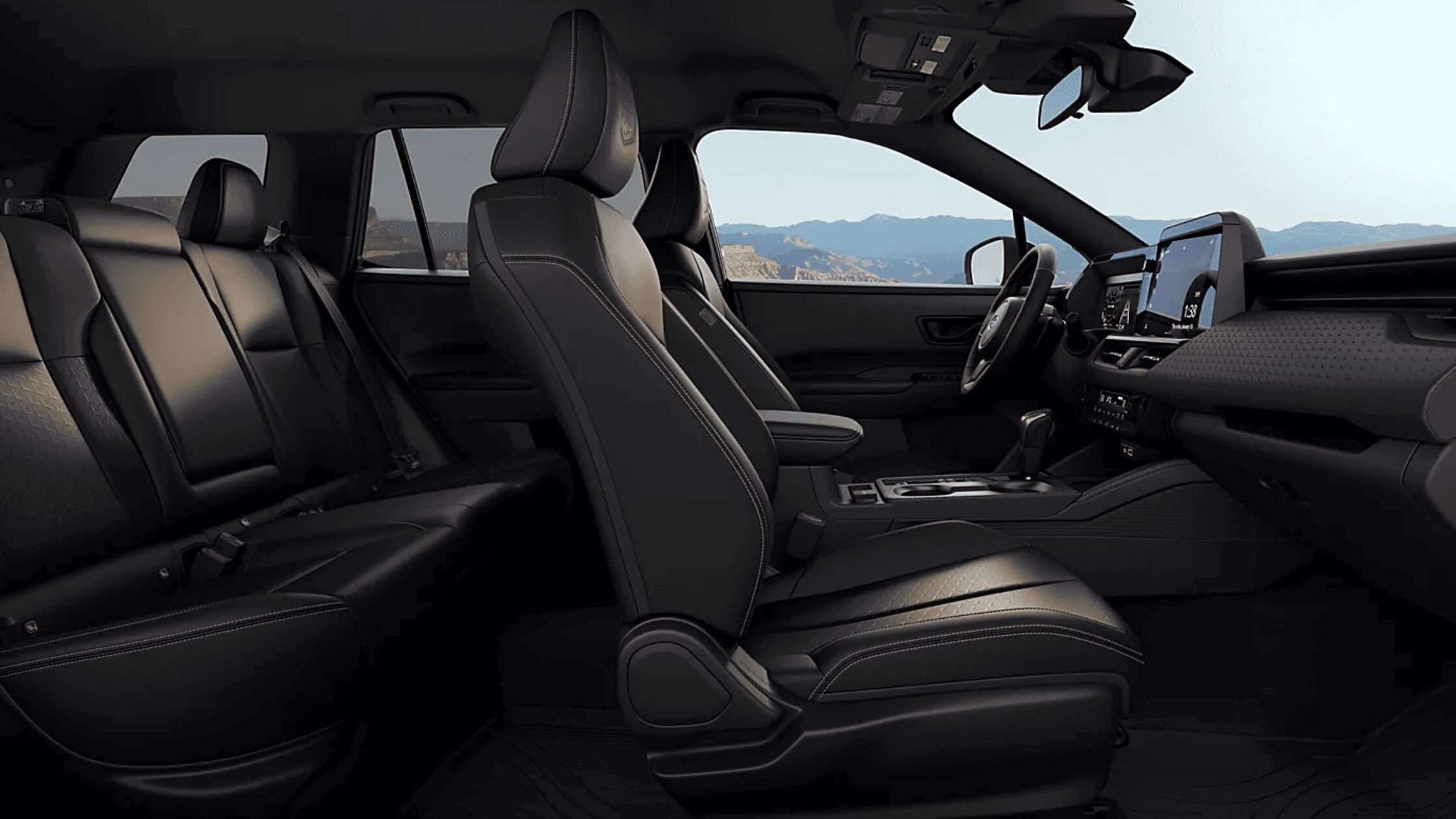 2026 Subaru Outback Wilderness all-black interior showing front and rear leather seats with touchscreen infotainment and mountain view through windows