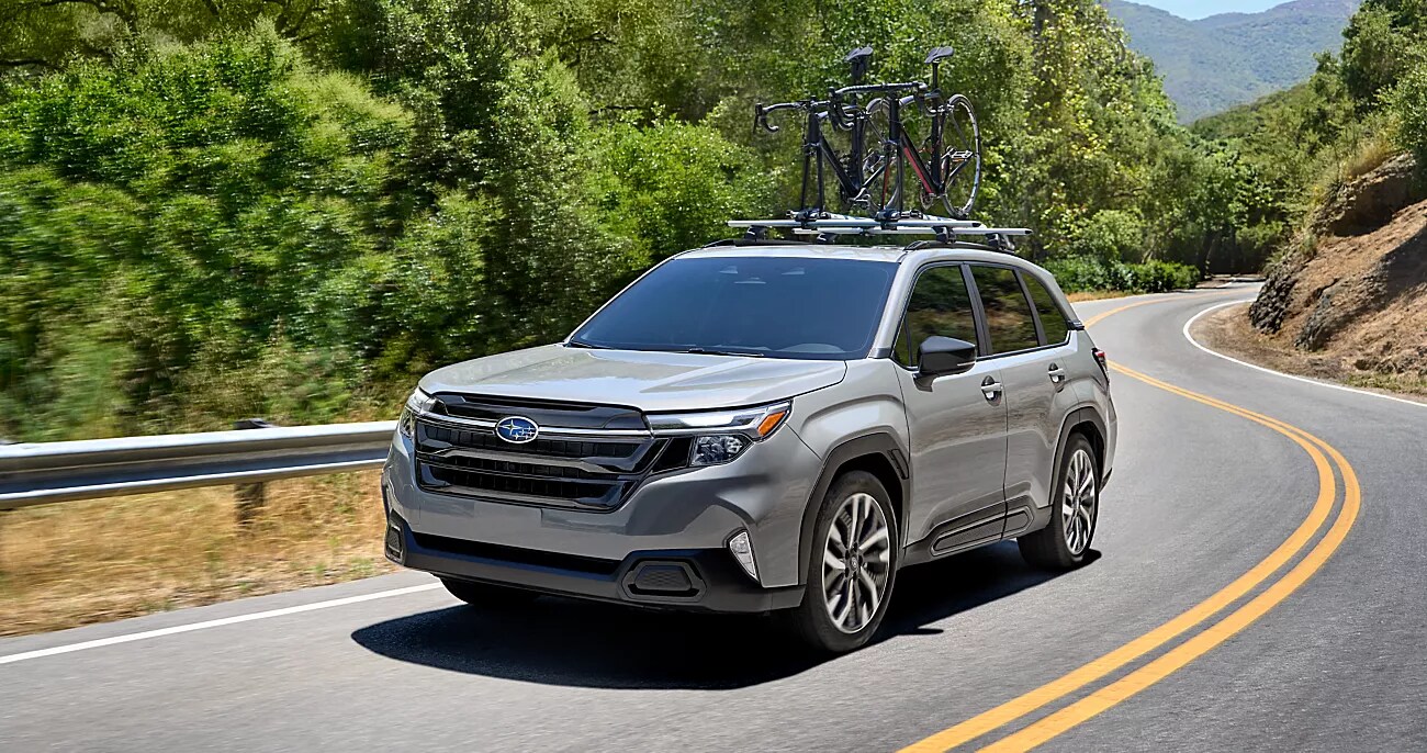 White 2025 Subaru SUV parked outside of brick industrial building with palm trees and succulent landscaping