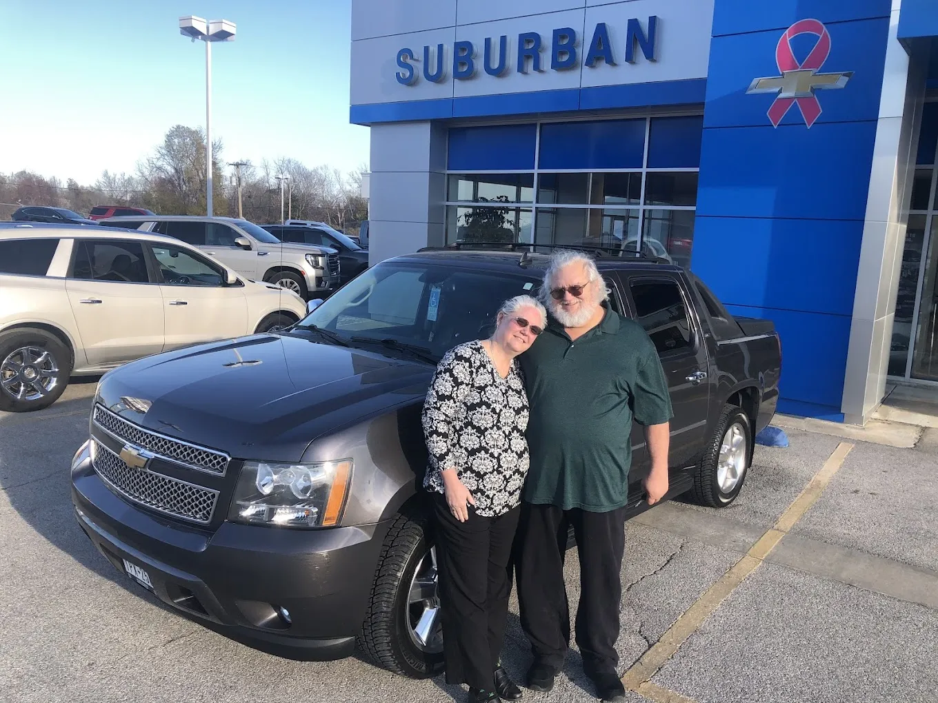 Happy couple posing next to a recently purchased Chevy truck